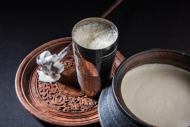 Lassi doce indiano feito de leite, requeijão, açúcar e sal misturado com cubos de gelo, servido em um copo de aço jumbo, preparado em panela de barro tradicional