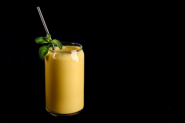 Lassi de mango en vidrio con tubo sobre fondo negro bebida tradicional india y pakistaní con yogur