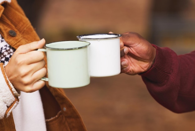 Lasst uns aufwärmen Schnappschuss eines Paares, das mit seinen Kaffeetassen anstößt, während es draußen in der Wildnis ist