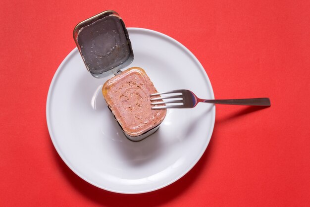 Lata aberta com carne em lata, mesa da cozinha com vista superior