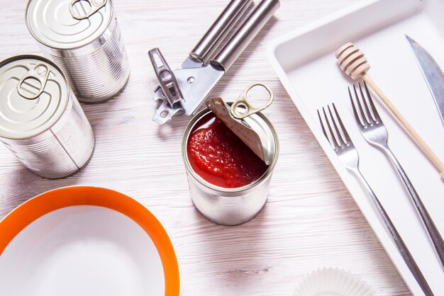 Lata aberta com tomates enlatados, na mesa da cozinha de madeira