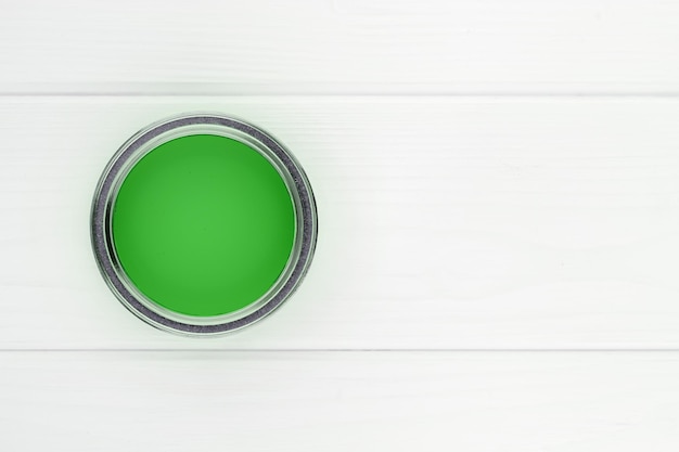 Lata abierta con pintura verde en una vista superior de fondo de madera blanca con espacio de copia
