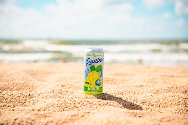 lata de aluminio cerveza Volfas Engelman menta limón mojito salpicadura producido lituano vacaciones playa de verano en el fondo borroso mar o océano cielo azul y nubes KlaipedaLituania07142023