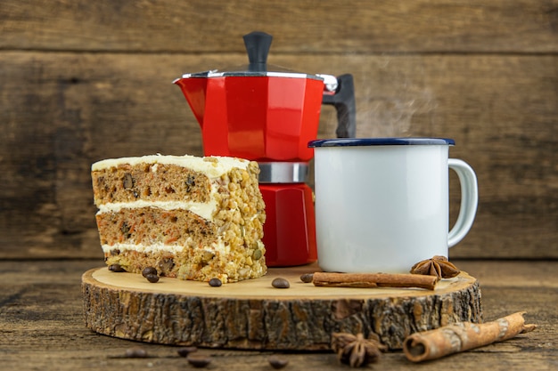 Una lata blanca taza de café caliente con cafetera italiana (Moka) y pastel en la mesa de madera.