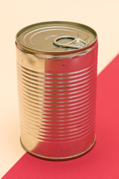 lata de hojalata sin abrir con borde en blanco sobre un fondo rojo y beige dividido