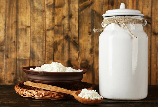 Lata de leche con tazón de requesón y cuchara sobre fondo de madera rústica