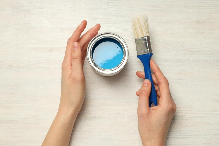 Lata con pincel y manos femeninas en la vista superior de fondo de madera