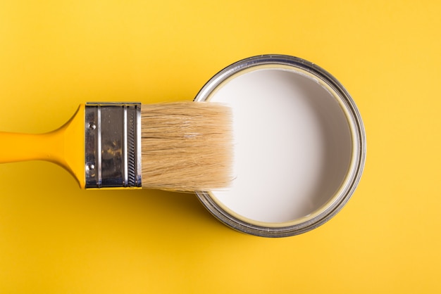 Lata de pintura blanca con pincel Vista superior sobre fondo amarillo