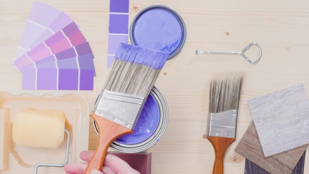 Lata de pintura metálica con pintura violeta y otras herramientas de pintura para proyectos de mejoras para el hogar.