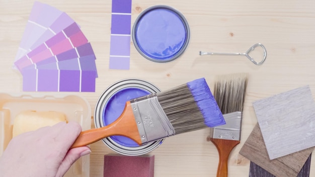 Lata de pintura metálica con pintura violeta y otras herramientas de pintura para proyectos de mejoras para el hogar.
