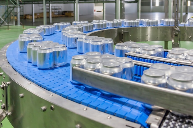 Las latas de aluminio para bebidas se mueven en la cinta transportadora en una gran fábrica.