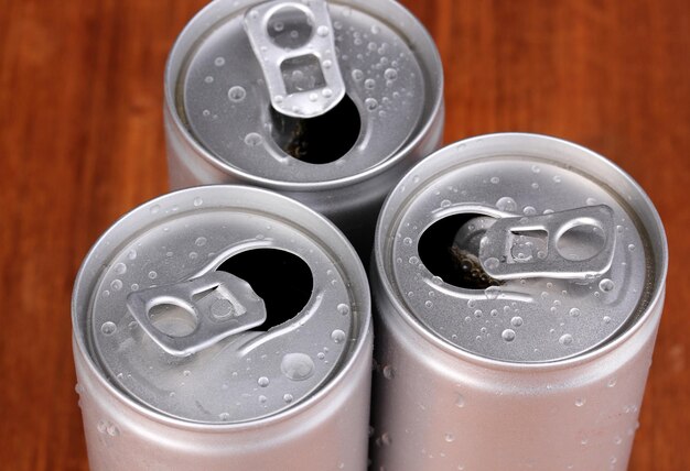 Foto latas de aluminio con gotas de agua sobre fondo marrón
