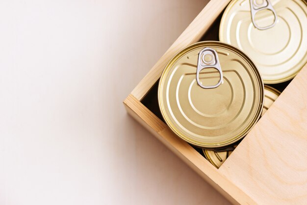 Latas en una caja. Una variedad de comida enlatada en latas llenas. Comida enlatada real. Vista desde arriba. Enfoque selectivo.