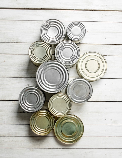 Latas con comida. En mesa de madera blanca.