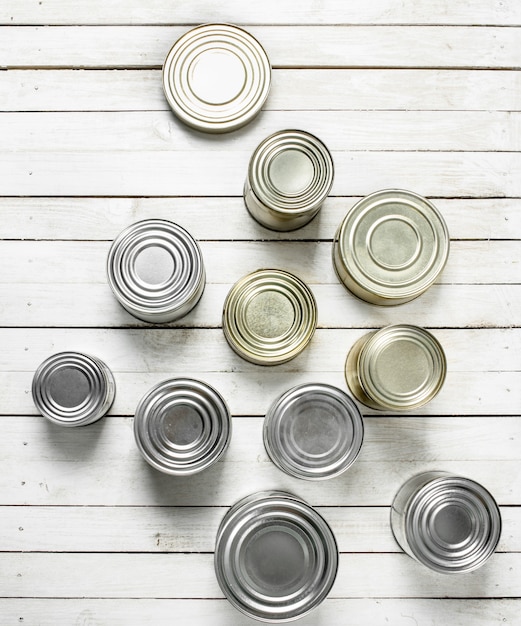 Latas con comida en la mesa de madera blanca.