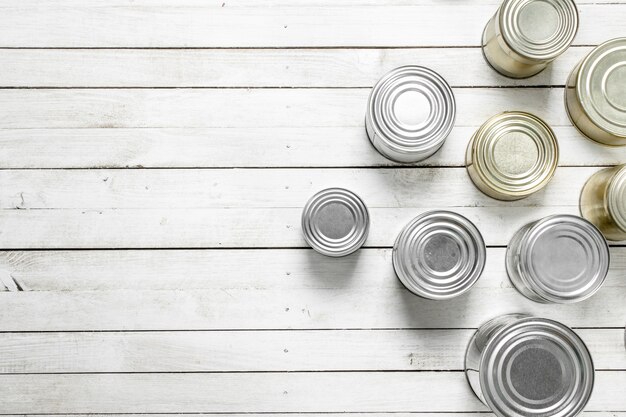 Latas con comida en la mesa de madera blanca.