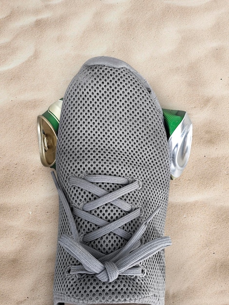 Latas de pisoteio de pé humano planas no mar de praia de areia