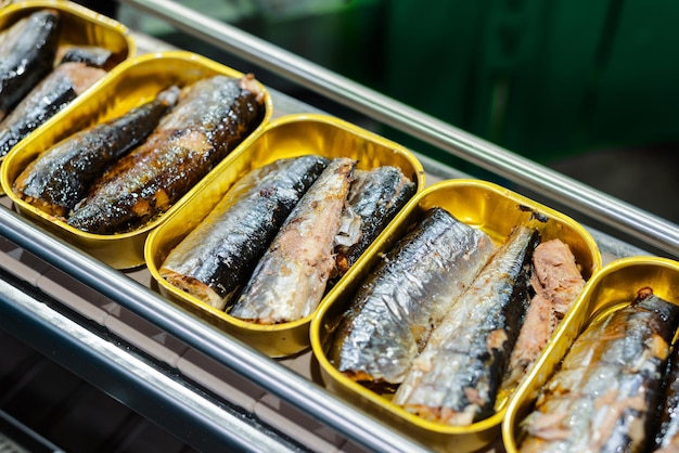 Latas de estaño con pescado en el transportador