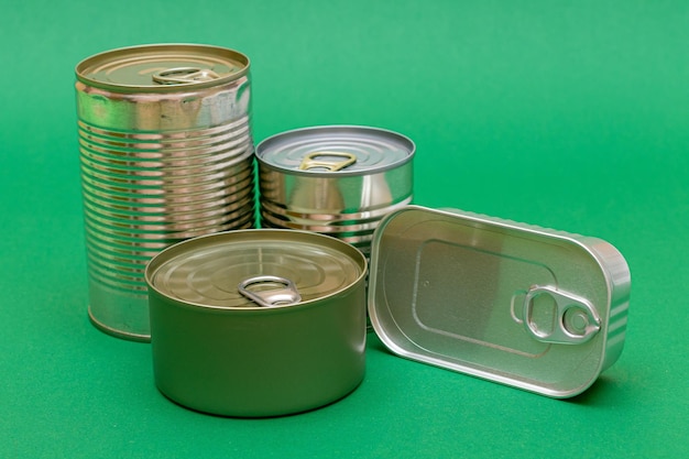 Foto latas de hojalata sin abrir con bordes en blanco sobre un fondo verde