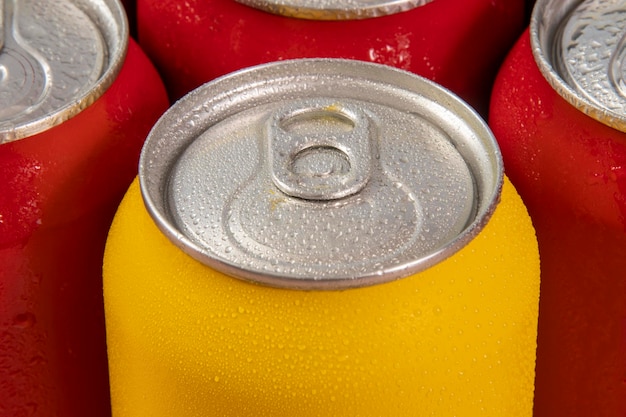 Latas de refresco rojo frío con una amarilla para uso conceptual