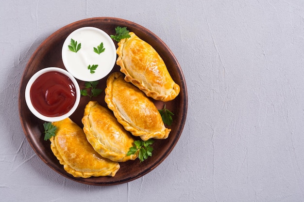 Lateinamerikanische gebackene Rindfleisch-Empanadas mit Saucen. Lebensmittelhintergrund