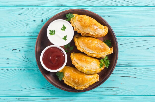 Lateinamerikanische gebackene Rindfleisch-Empanadas mit Saucen. Lebensmittelhintergrund