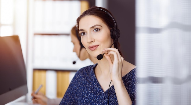 Lateinamerikanische Geschäftsfrau, die per Headset im Büro spricht. Call Center und diverse Personengruppen in der Wirtschaft.