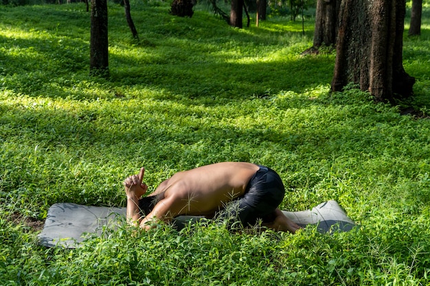Lateinamerikanischer Mann macht Yoga-Haltung Yoga-Haltung Biene rückwärts Prsthatah Brahmara Wald