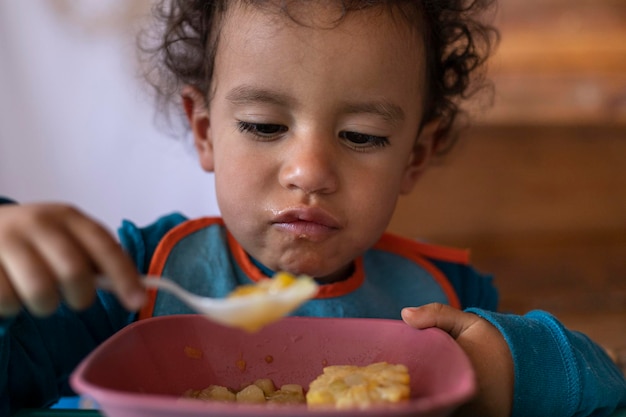 Foto lateinamerikanisches kind 2, das suppe mit gemüse zum mittagessen isst, lernte, im kindergarten alleine zu essen konzept der kindheit und des lernens