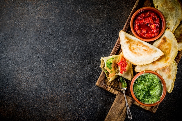 Lateinamerikanisches, mexikanisches, chilenisches Essen. Traditionelle Empanadas aus gebackenem Gebäck mit Rindfleisch, zwei scharfen Soßen