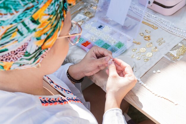 Lateinische Frau, die handgefertigten Steinschmuck zu Hause herstellt Handwerkerin, die Schmuck herstellt Kunst-Hobby-Handwerkskonzept