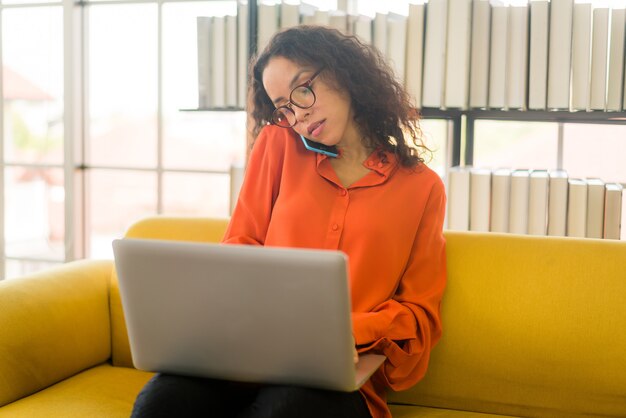 lateinische frau, die zu hause mit laptop auf sofa arbeitet