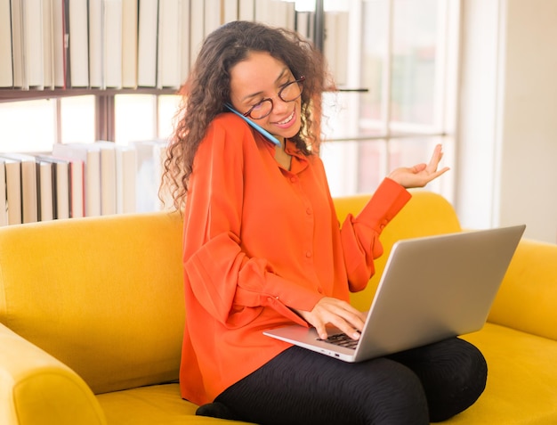 lateinische frau, die zu hause mit laptop auf sofa arbeitet