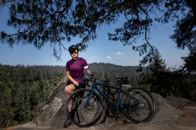 Lateinische Frau mit Fahrrad ruht im Wald mit einer Landschaft von Bäumen im Hintergrund