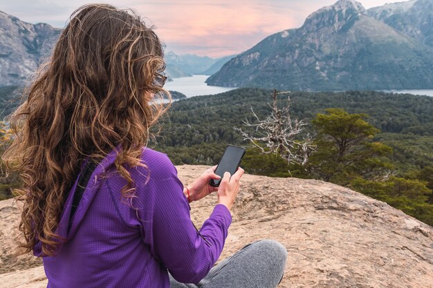 Lateinische Frau mit Handy in Berglandschaft