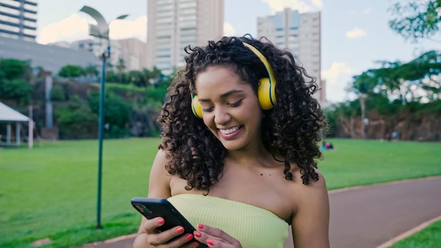 Lateinische Frau mit Smartphone im Park. Brasilianisches Mädchen.