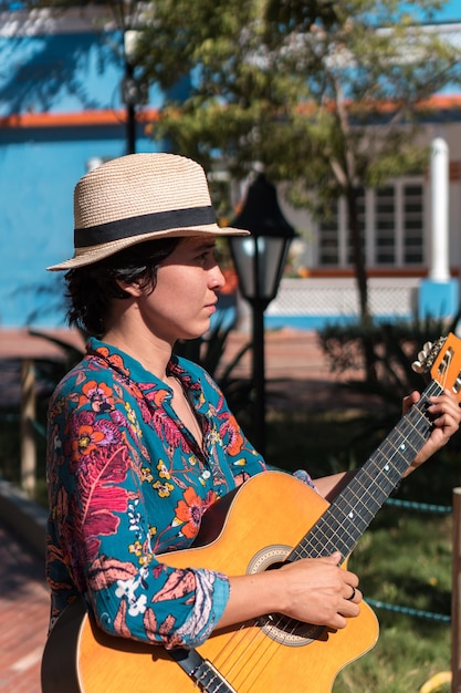 Foto lateinische frau spielt gitarre, stehend auf park