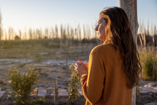 Lateinische Frau trinkt Kaffee und beobachtet den Sonnenuntergang