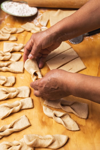 Lateinische Frauenhände kneten Teig auf einem Holztisch Chilenisches frittiertes Gebäck Lateinisches Essen