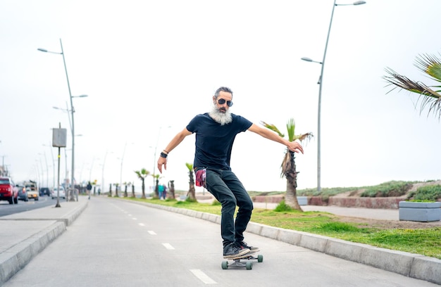 Lateinischer älterer Mann Skateboard auf Radweg und Spaß in La Serena