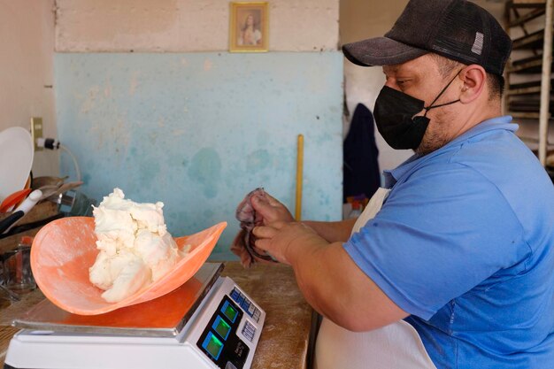 Lateinischer Bäcker mit Maske, der in einer traditionellen mexikanischen Bäckerei und Konditorei arbeitet.