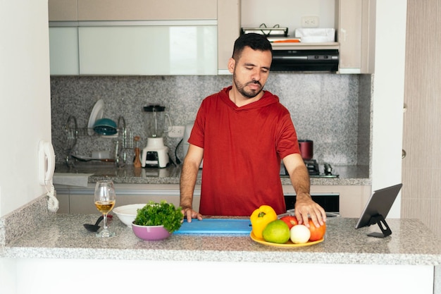 Lateinischer Mann, der Gemüse auswählt, um einen Salat zuzubereiten