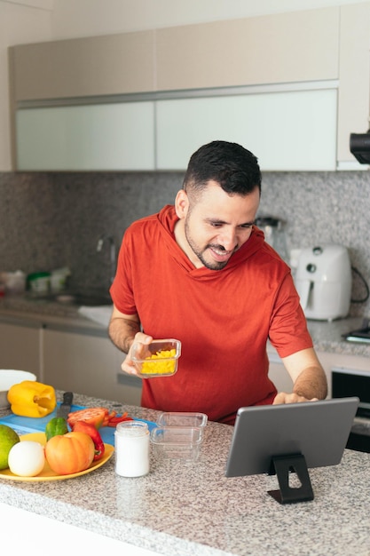 Lateinischer Mann kocht und benutzt sein Tablet in der Küche