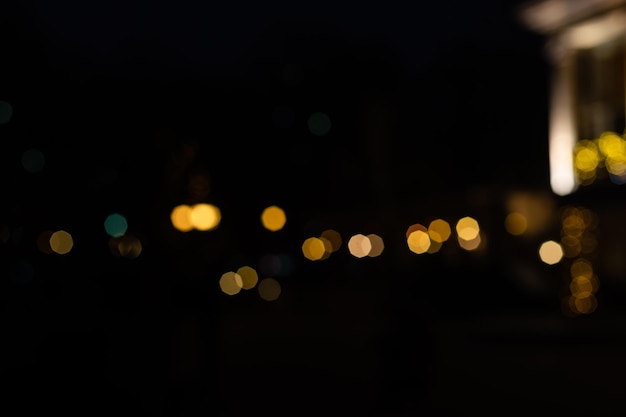 Laterne der Cafébeleuchtung leuchten mit warmem Licht im Nachtgarten des Hinterhofs im Hintergrund Bokeh-Kugeln aus der Girlande an der Fassade des Restaurantgebäudes, niemand.