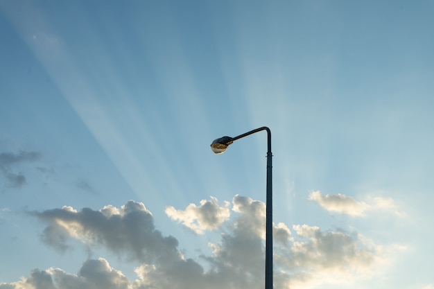 Laternenpfahl am Abendhimmel mit den Strahlen der untergehenden Sonne.