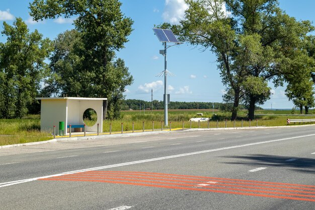 Laternenpfahl mit Solarpanel-System auf der Straße mit blauem Himmel und Bäumen Autonome Straßenbeleuchtung mit Sonnenkollektoren Straßenlaterne auf Batterien von der Sonne Alternative erneuerbare Energiesysteme