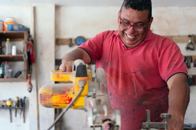 Latin carpenter usando uma serra circular na oficina