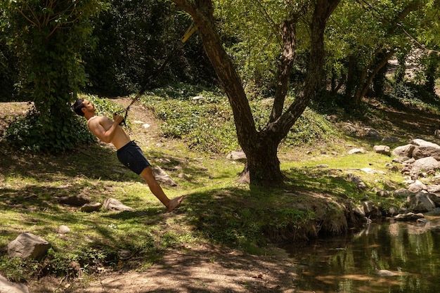 Latin Fit jovem está treinando ao ar livre no espaço TRX Copy