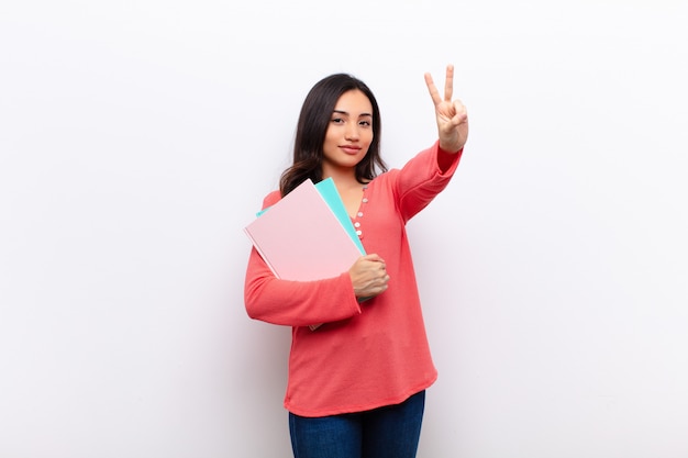 Latina bonita jovem contra a parede plana com livros