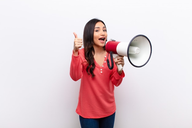 Latina bonita jovem contra a parede plana com um megafone